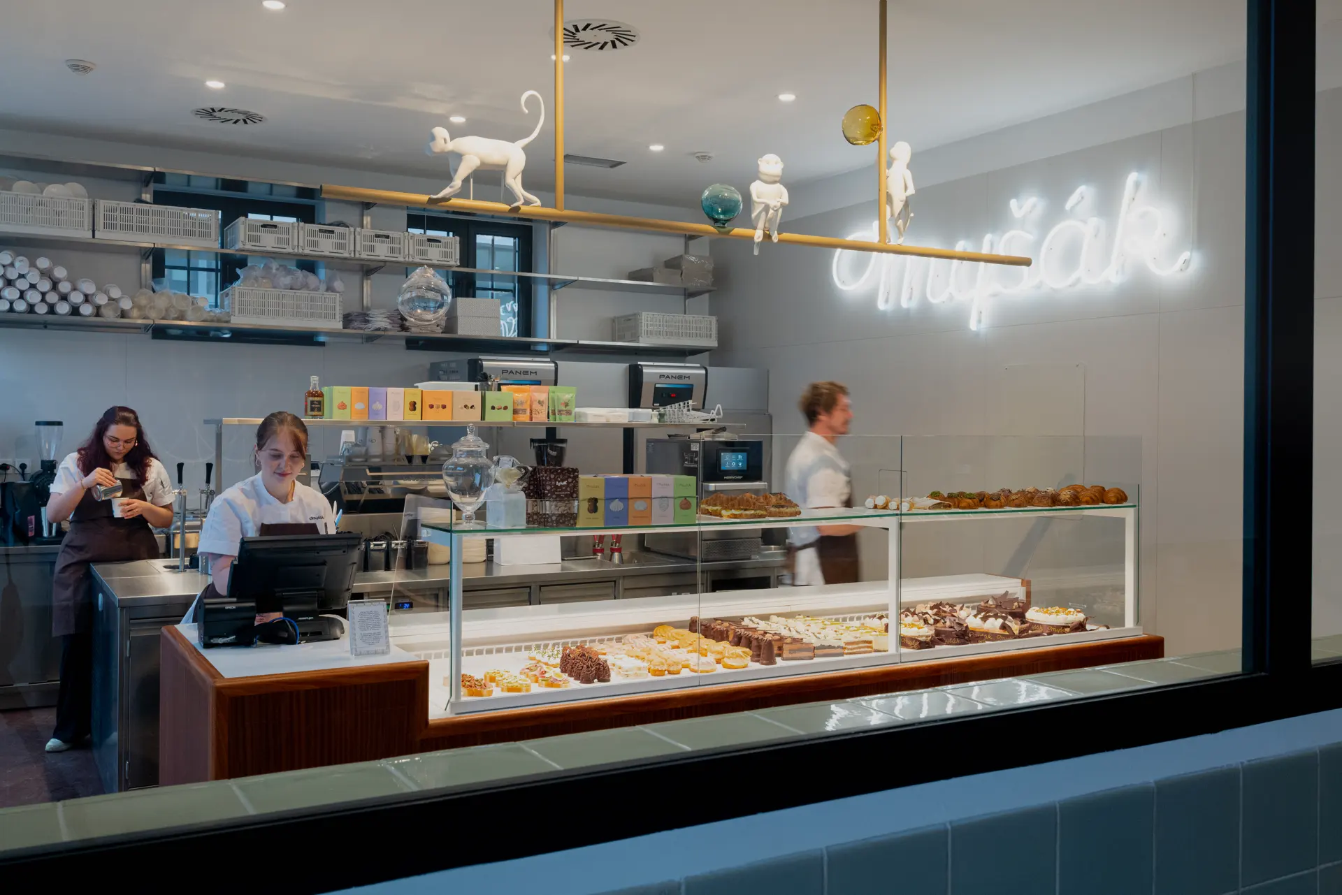 Interiér cukrárny Myšák s obsluhou a vitrínou dezertů.